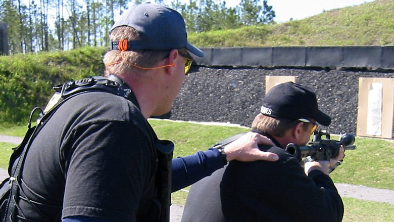 Two men training on an outdoor rifle range.